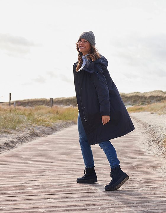 Ein Fest für mich: Frau genießt einen Winter-Spaziergang an der Nordsee, dick eingepackt in Jacke, Schal und Mütze.