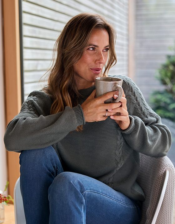 Sinnvolle Neujahrsvorsätze: Eine Frau genießt eine Tasse Tee am Fenster