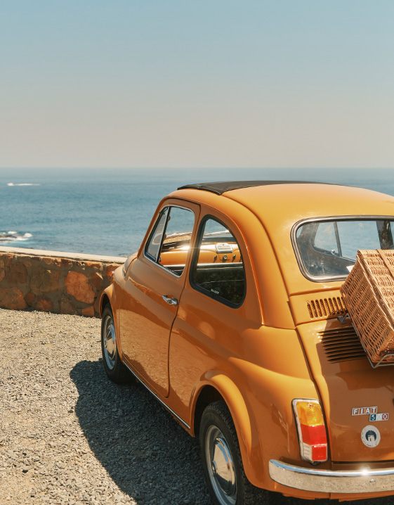 Dolce Vita - ein gelber Fiat 500 parkt an einem Aussichtspunkt mit Meerblick