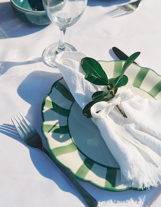 Dolce Vita - Geschirrservice auf weißer Tischdecke mit Serviette und Olivenzweigchen